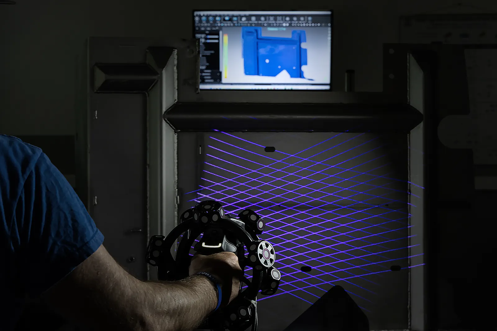 3D scanning in a darkened room: structured-light scanner projecting a blue grid onto a part